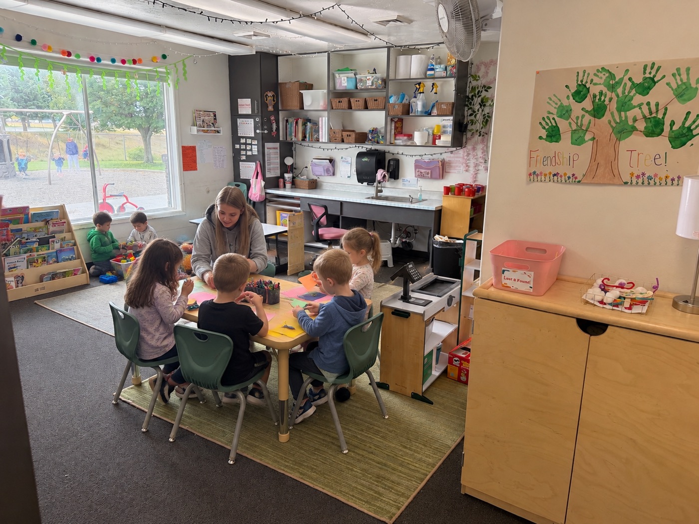 Early learners doing a craft at a table with their teacher