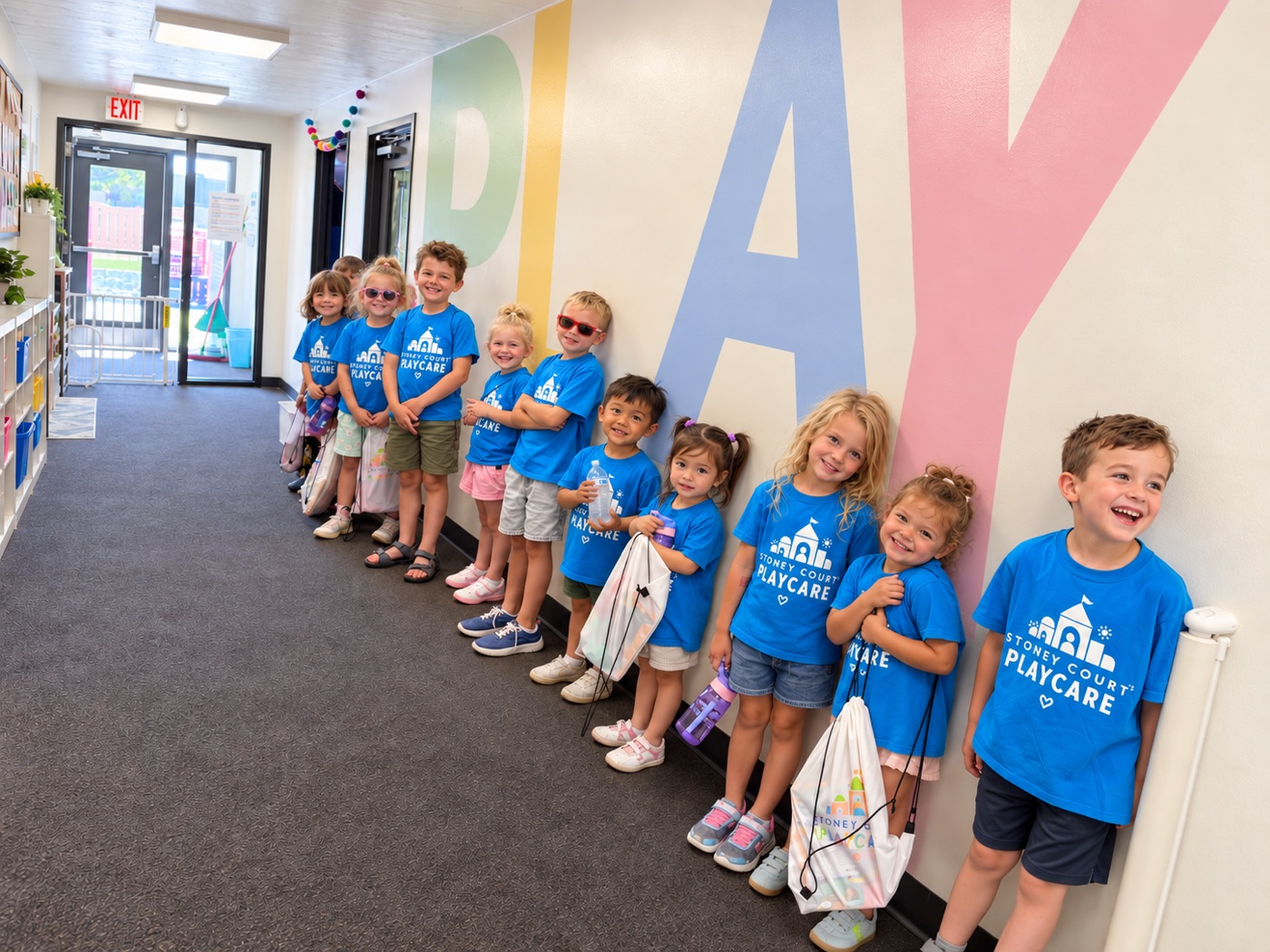 Stoney Court kids in matching Playcare shirts lined up by our PLAY wall
