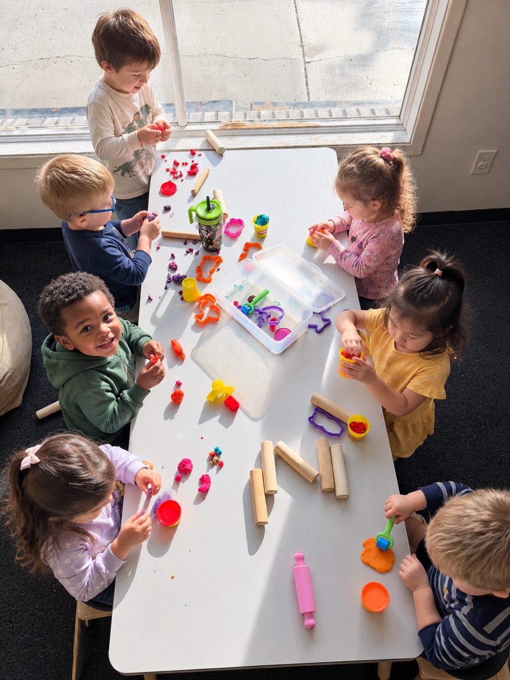 Preschoolers playing with play dough at a table